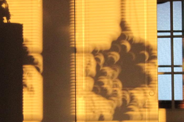 Osittaisen auringonpimennyksen aikana näkynyt sirppi varjojen väleissä neulanreikäkameran periaatteella.