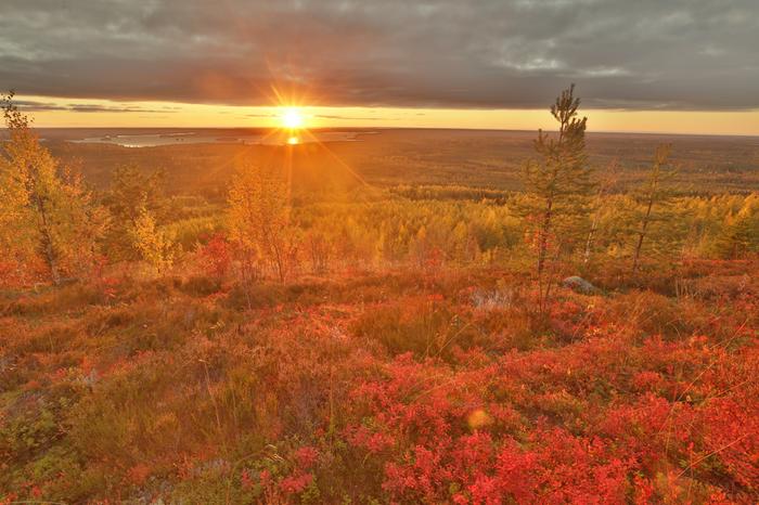 Aurinko laskee vaaran taa ja värjää maiseman punaisella.