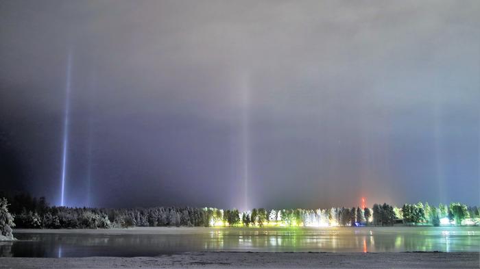 Pakkasta, kevyttä lumisadetta ja keinovalopilareita kylän valoista.