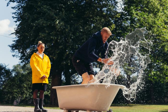Roni Bäck tyhjentää ammetta vedestä Suurmestarin kuvauksissa. Tuomari Pilvi Hämäläinen seuraa suoritusta.