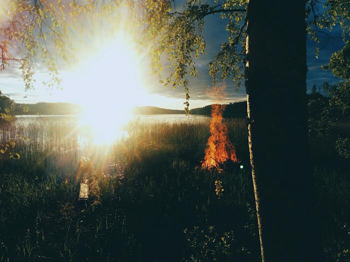 Juhannuskokon polttoa järven rannalla auringonlaskun aikaan.