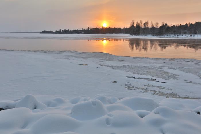 Aurinko talvipäivänä sulan veden yllä.