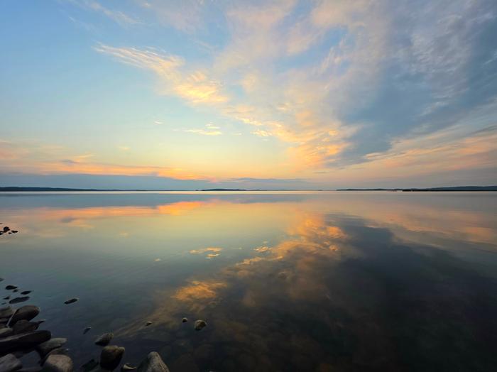 Pilvet heijastuvat tyynestä järvenpinnasta.