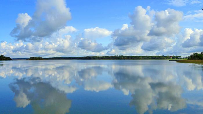 Pilvet peilaantuvat järven pinnasta Kumpupilviä muodostuu usein päiväsaikaan.