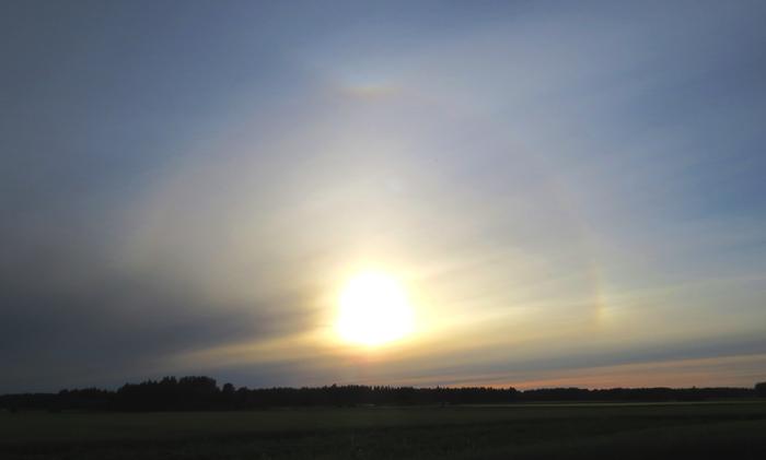 Auringon ympärillä näkyy useita haloilmiöitä: 22 asteen rengas ja 22 asteen ylläsivuava kaari sekä sivuaurinko.